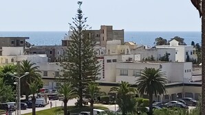 Un paysage urbain côtier avec des bâtiments, des palmiers et une vue dégagée sur la mer.
