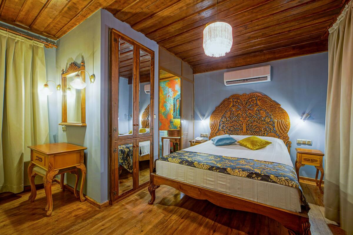Una habitación con paneles de madera, una cama, un espejo, una lámpara de araña y un equipo de aire acondicionado.