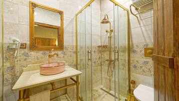 A bathroom with a glass-enclosed shower, a vanity with a pink basin, and a wooden door.