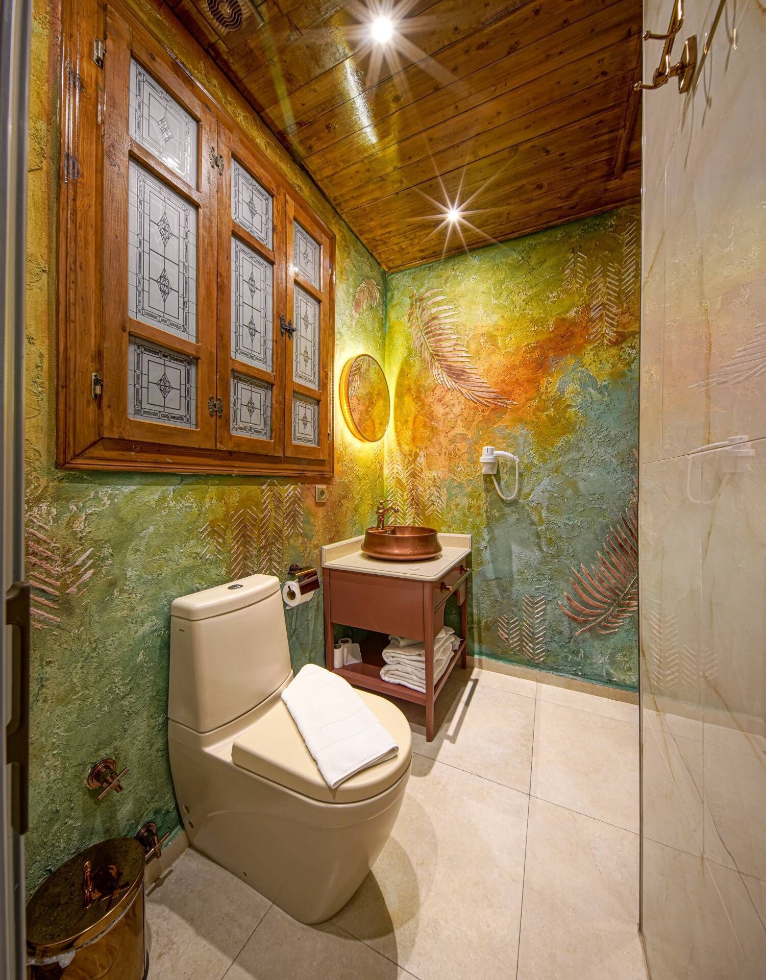 A bathroom with a toilet, a sink with a copper basin, and a mirror.