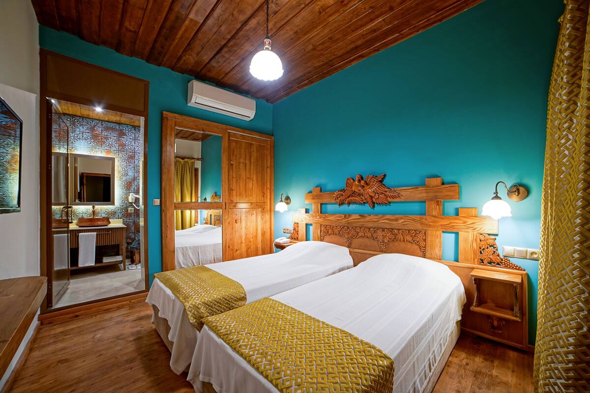Una habitación con dos camas, cabecero de madera, un espejo y techo de madera.