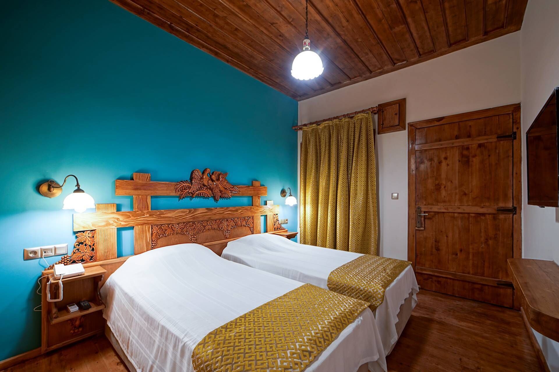 A double bed with a wooden headboard, a nightstand with a lamp, and a wooden wardrobe.