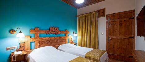 A double bed with a wooden headboard, a nightstand with a lamp, and a wooden wardrobe.