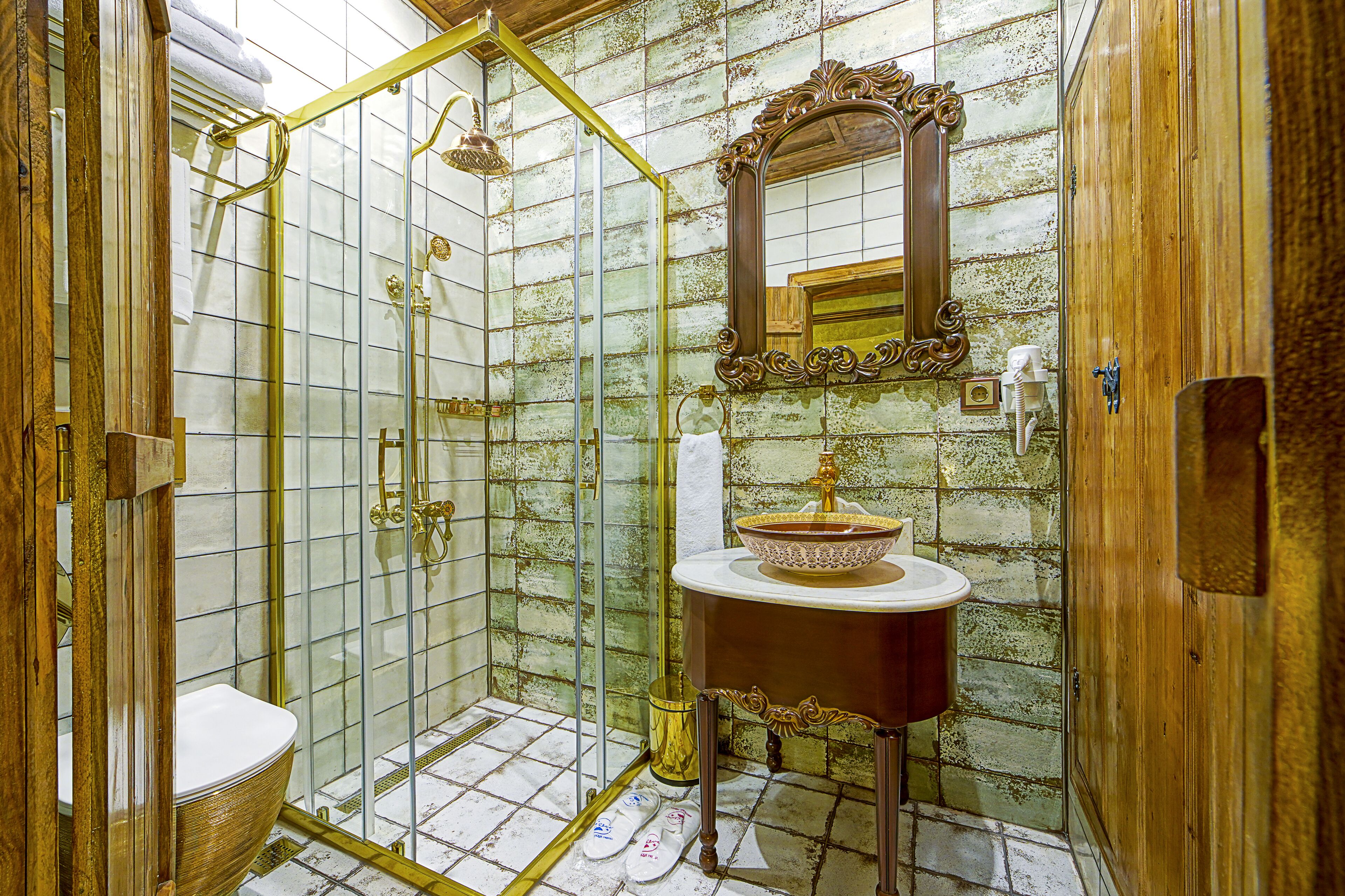 Casa de banho com cabine de chuveiro envidraçada, toucador de madeira com espelho e lavatório branco.