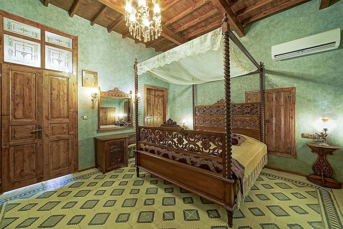 Una cama con dosel, un armario de madera y un espejo.