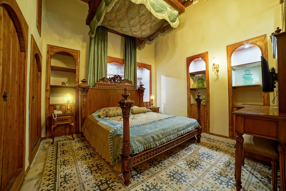 Un dormitorio tradicional con cama con dosel, muebles de madera y baldosas estampadas.