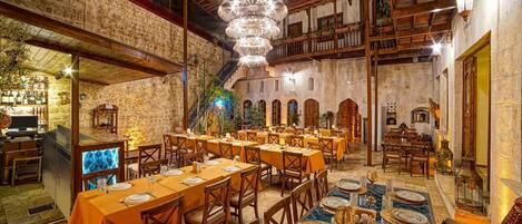 Un restaurante con varias mesas dispuestas para comensales, una zona de bar y una escalera que conduce a un nivel superior.