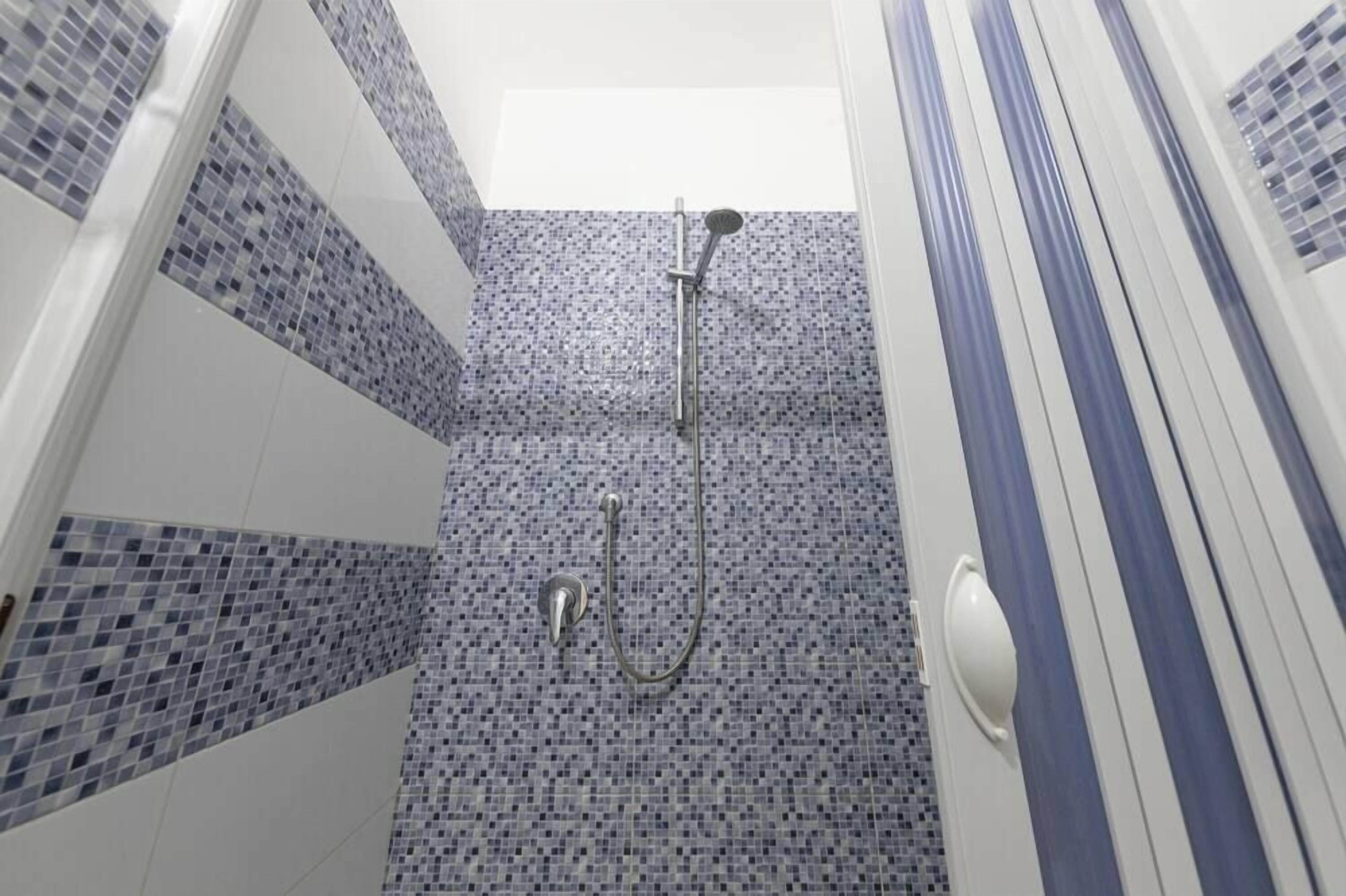 A bathroom with a shower, tiled walls, and a striped curtain.