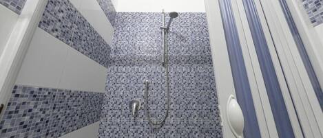 A bathroom with a shower, tiled walls, and a striped curtain.
