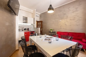 A compact living space with a dining area, a red sofa, and a kitchen with modern appliances. - Lovely New Home, Via Genova (Roma)