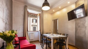 A modern living room with a dining area, a flat-screen TV mounted on the wall, and a window with curtains. - Lovely New Home, Via Genova (Roma)