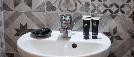 A bathroom sink with a modern faucet and two toiletries on the counter.