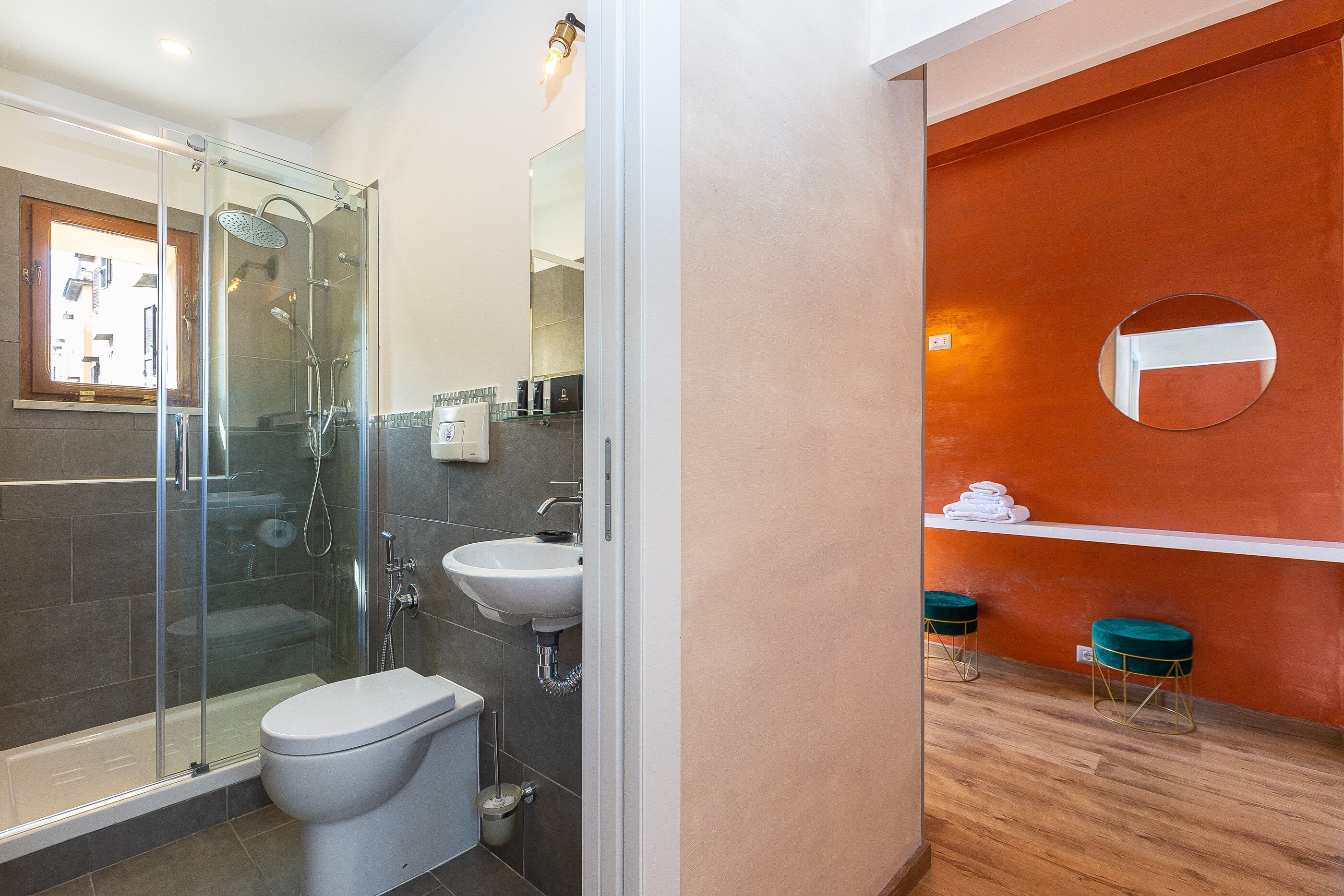 A modern bathroom with a glass-enclosed shower, a white sink, and a wooden floor.