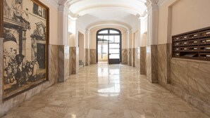 A marble-floored corridor with a large framed historical painting on the left, arched ceilings, and a wooden storage unit on the right. - Lovely New Home, Via Genova (Roma)
