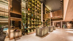 Eine moderne Hotelhalle mit einer großen, gut beleuchteten Präsentation dekorativer Objekte, Marmorböden und einer Treppe zu den oberen Etagen.