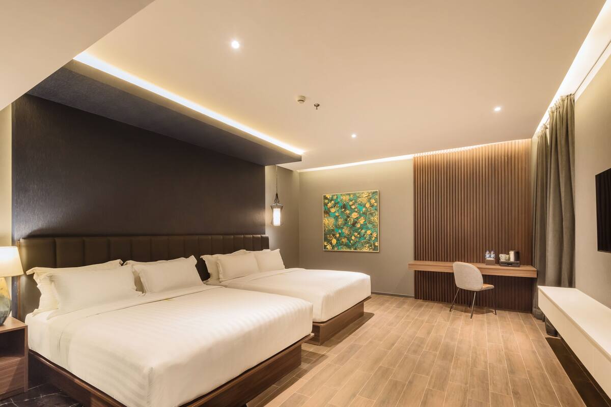 Une chambre d’hôtel avec deux lits, un bureau, une chaise et un téléviseur.