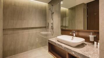 A modern bathroom with a large mirror, a sink, and a shower.
