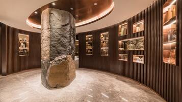 A lobby with a large stone column, wooden paneling, and glass display cases.
