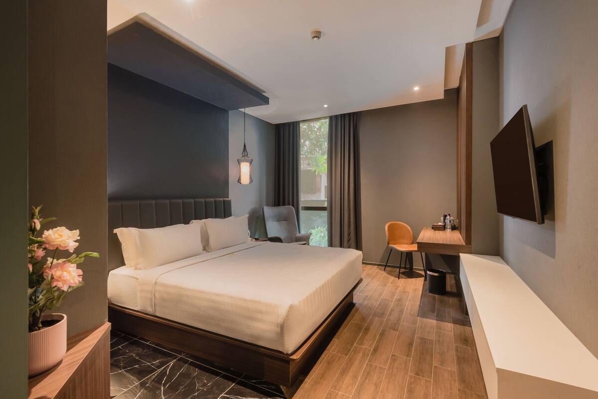 Une chambre d’hôtel moderne équipée d’un grand lit, d’un bureau, d’une chaise et d’un téléviseur.