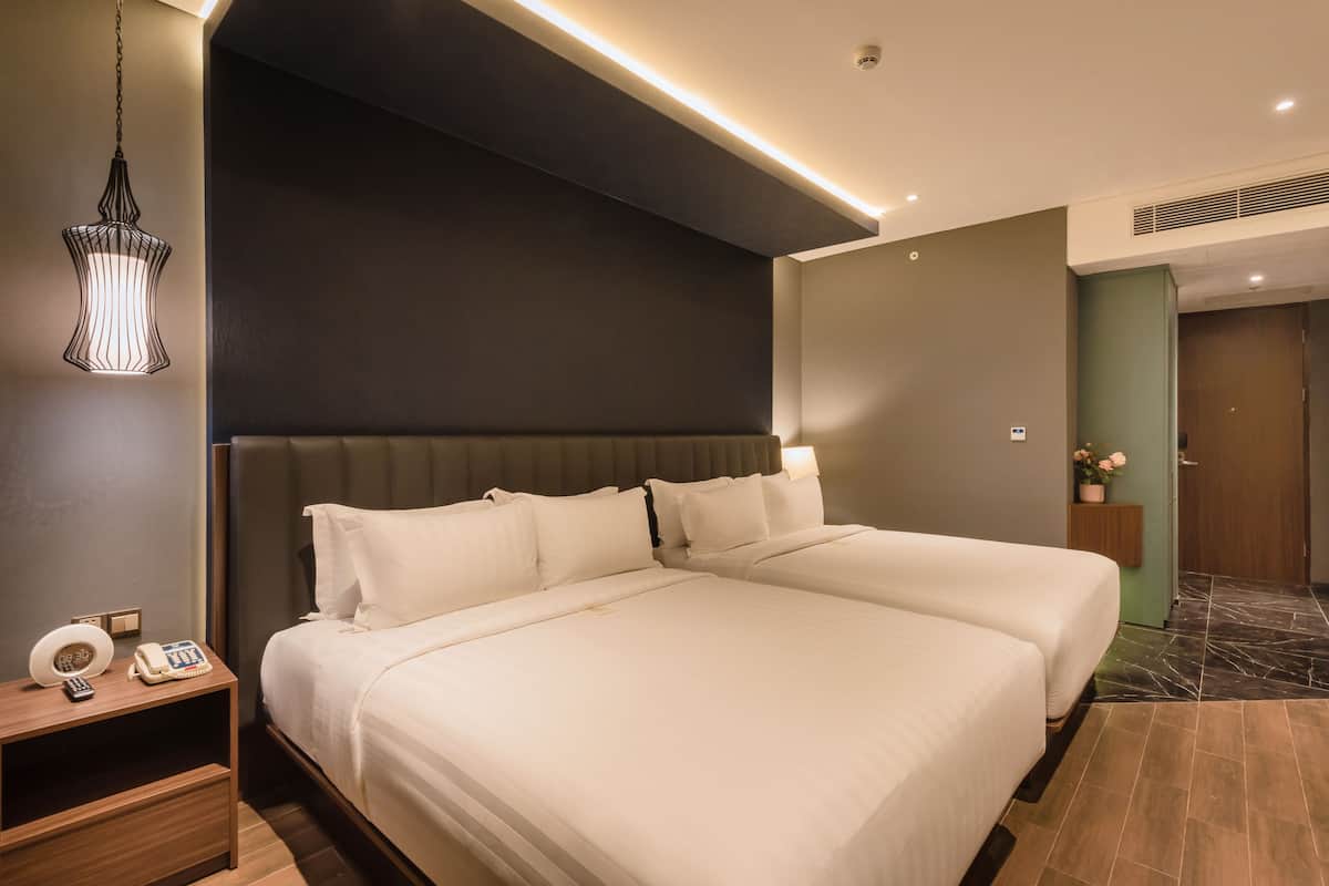 Une chambre d’hôtel avec un grand lit, des tables de chevet, un téléphone et un luminaire suspendu.