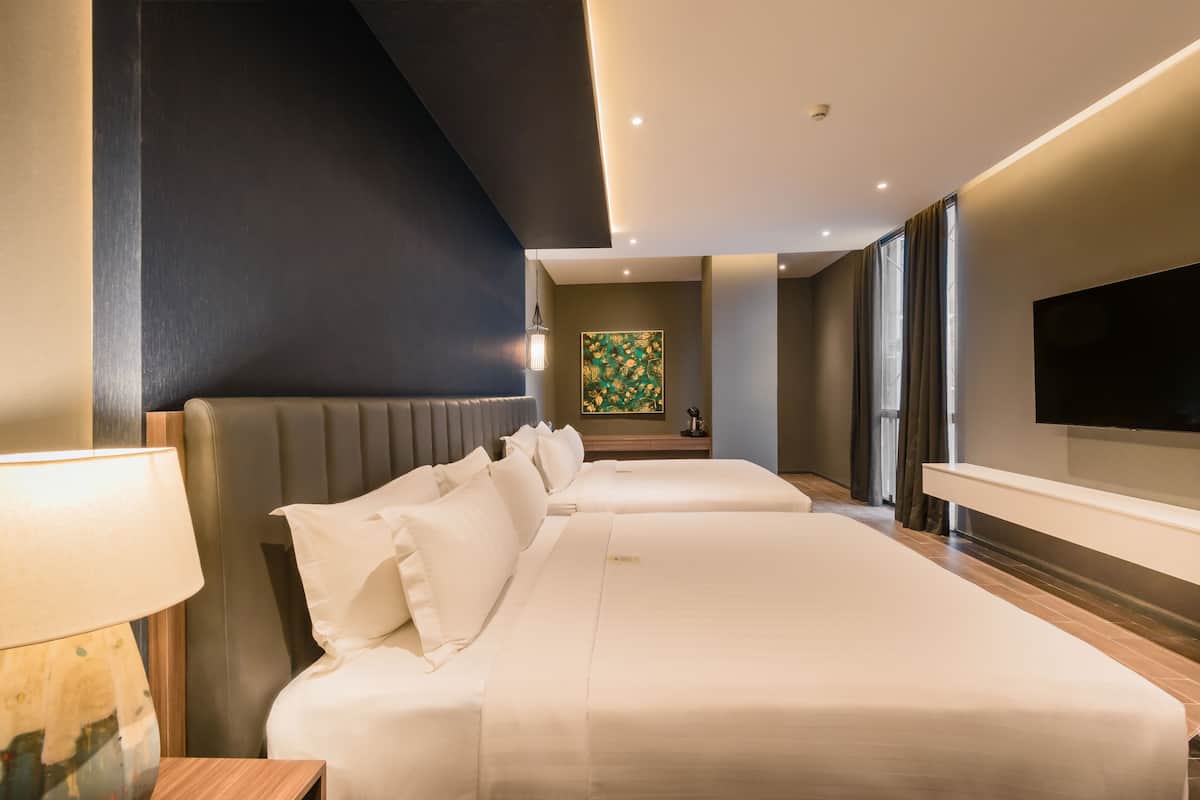 Une chambre d’hôtel moderne dotée d’un grand lit, d’un téléviseur à écran plat et offrant une vue sur le paysage urbain.