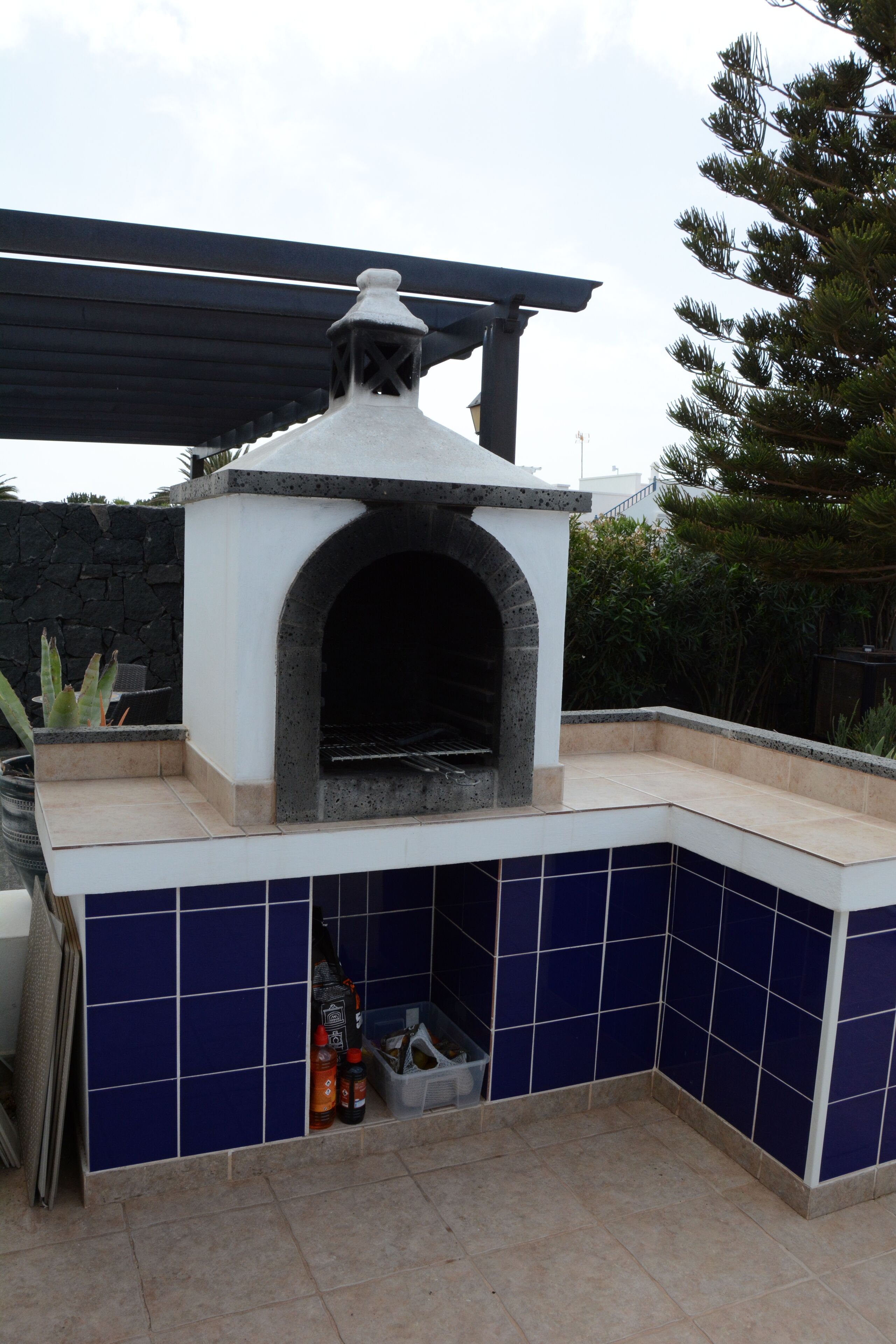 Un horno para pizza al aire libre, con fachada de piedra y base de azulejos.
