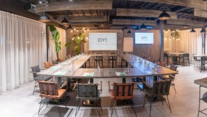 Une salle de conférence avec une longue table, des chaises et un écran affichant le texte « JOY5 HOTEL & SPA ».