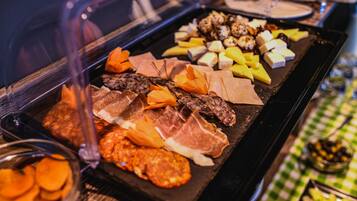 A buffet with various meats, cheeses, and fruits.