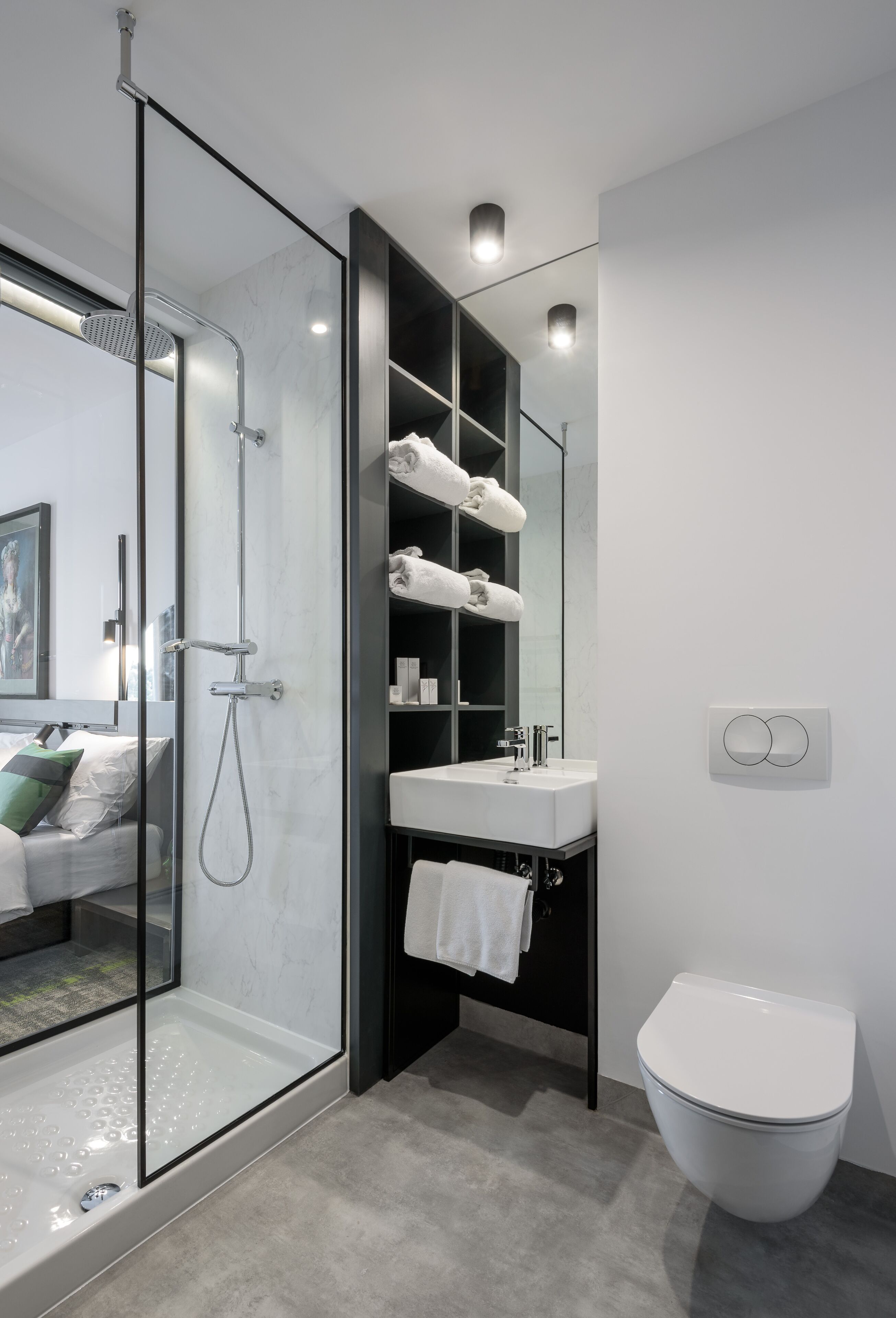Een moderne badkamer met een douche met glazen wand, een witte wastafel en een toilet.