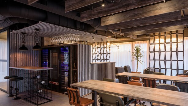 Un intérieur moderne avec des plafonds apparents, des meubles de style industriel et un mélange d’éléments en bois et en métal.