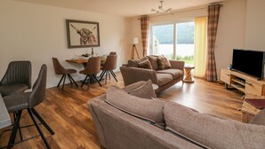 A modern living room with a sofa, chairs, a dining table, and a TV. - Lochy Lookout (Spean Bridge)