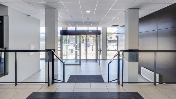 A modern building entrance with a glass door, metal railings, and a tiled floor. - Apparteo Toulouse (Toulouse)