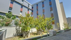 A modern building with a flat roof, multiple balconies, and potted plants in the foreground. - Apparteo Toulouse (Toulouse)