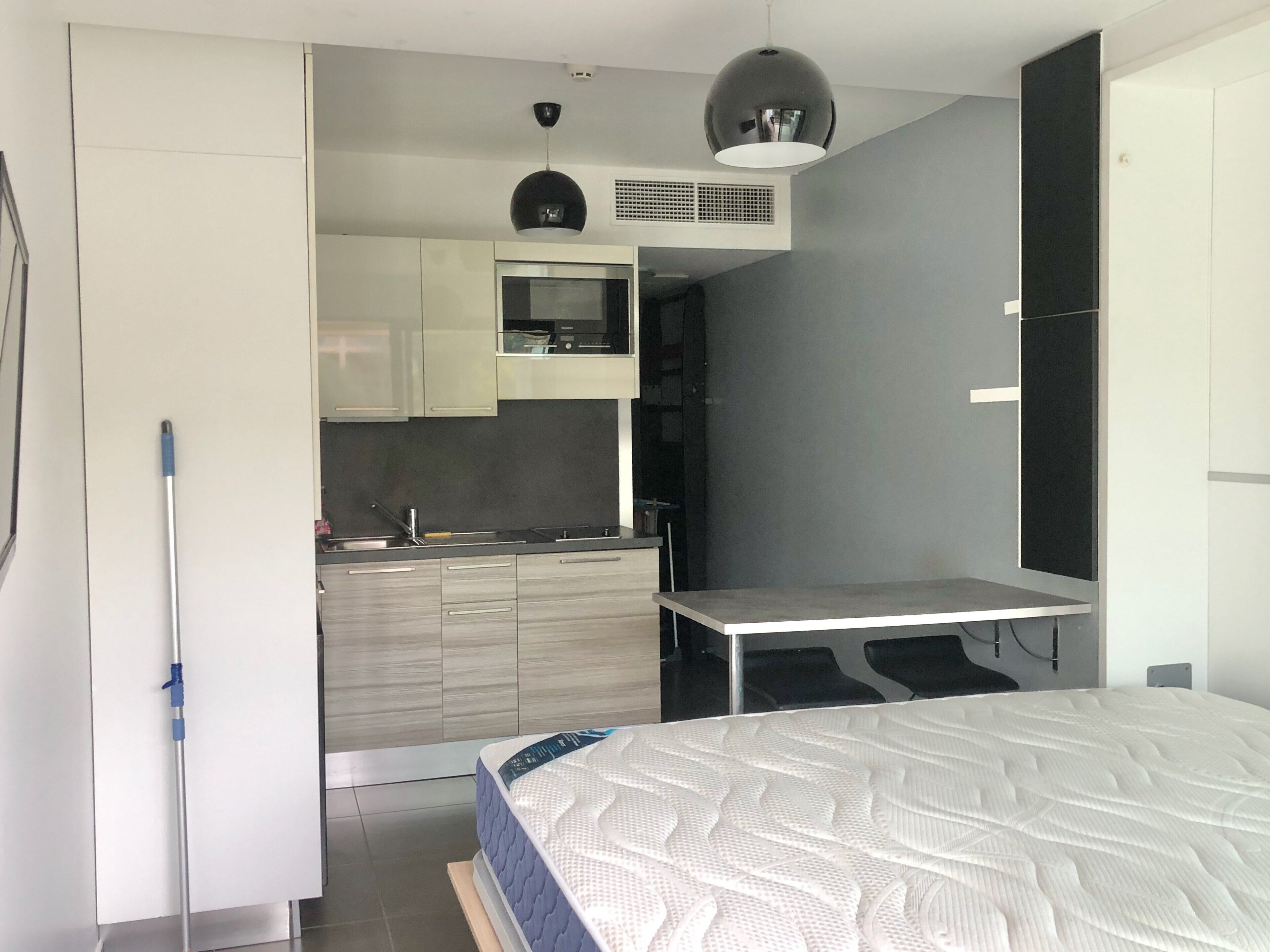 Een knus slaapkamer met een bed, een klein kitchenette en een bureau.