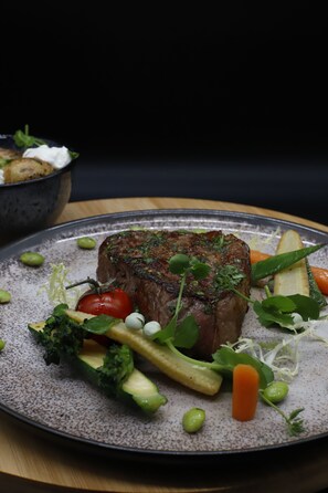 Une assiette avec un steak, des légumes et un petit bol en arrière-plan.