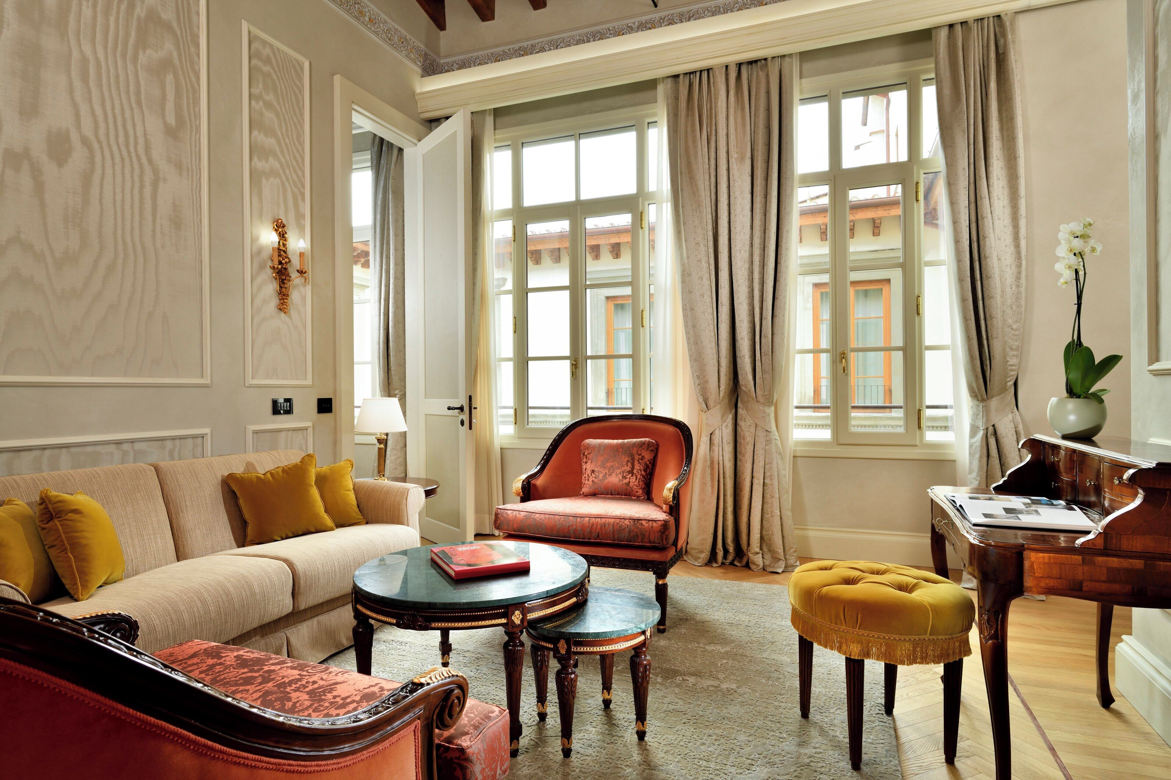 Un salon spacieux avec un canapé beige, un fauteuil rouge, une table basse et un piano.