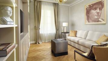 A living room with a sofa, ottoman, and a television on a cabinet.