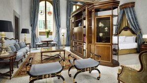 Una habitación lujosa con un amplio armario de madera, una cama y una zona de estar con sofá y sillones.