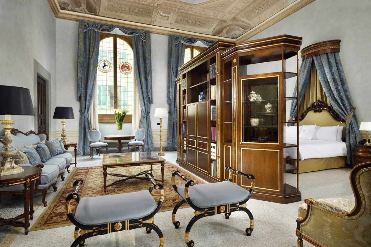 Una habitación lujosa con un amplio armario de madera, una cama y una zona de estar con sofá y sillones.
