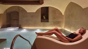 Eine Person entspannt sich in einer Badewanne mit Blick auf das Wasser und einem Fenster mit Blumen.