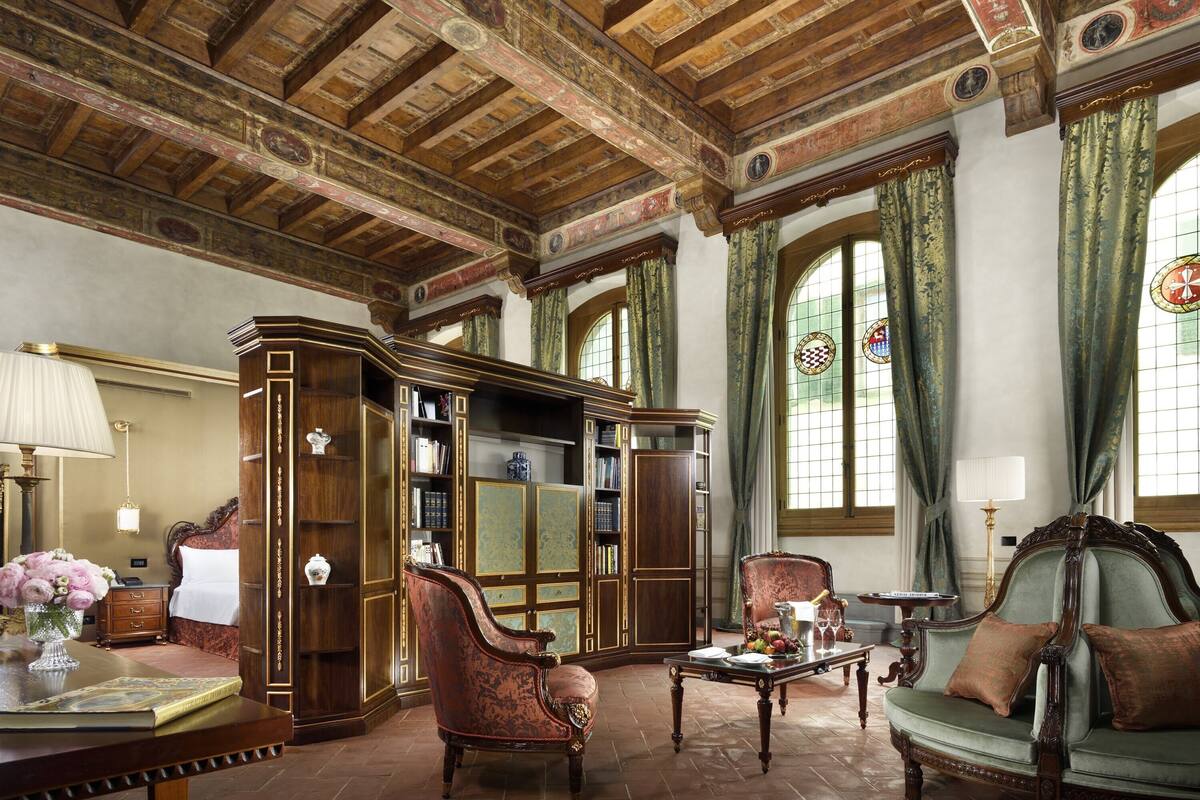 Una biblioteca tradicional con estanterías de madera, un sofá verde y vigas ornamentales en el techo.