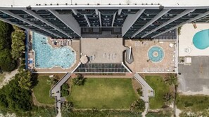 A high-rise building with a rooftop pool, a separate circular pool, and a landscaped area with pathways.