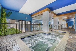 An indoor pool area with a waterfall feature, a stone-tiled floor, and a blue and white color scheme.