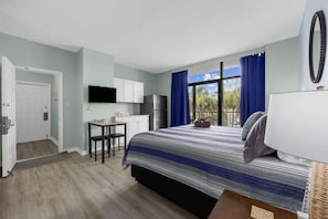 Un dormitorio con cama, escritorio, televisión y vistas al exterior.