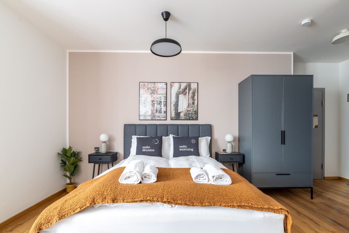 Een moderne hotelkamer met een groot bed, twee nachtkastjes, een kledingkast en twee kunstwerken aan de muur.