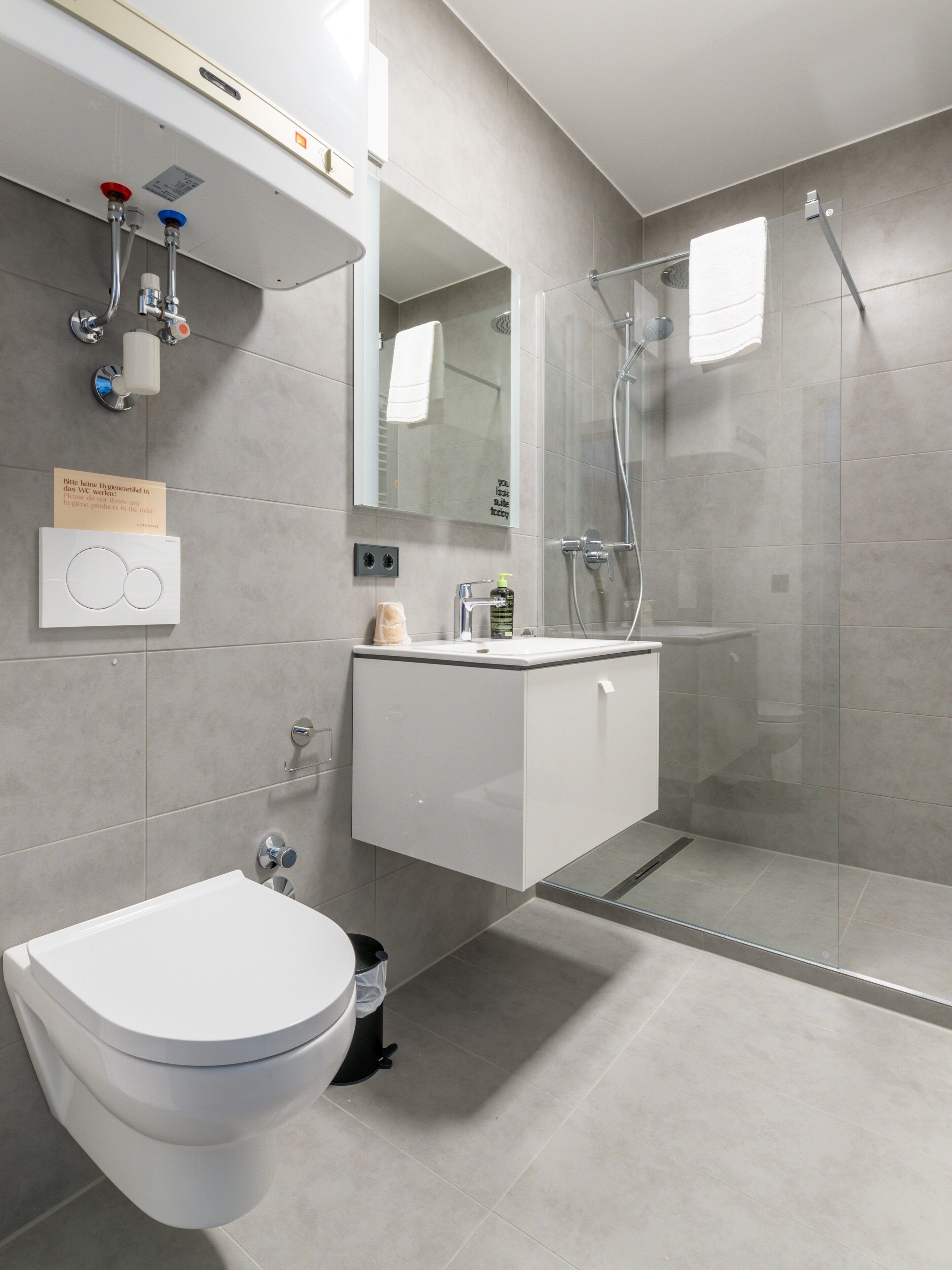 Un baño moderno con inodoro, lavamanos y ducha.