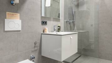 Un baño moderno con inodoro, lavamanos y ducha.