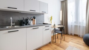 Uma cozinha moderna com armários brancos, uma pia de aço inoxidável e uma mesa de jantar de madeira com cadeiras.