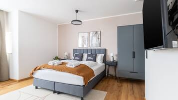 Un dormitorio moderno con cama, mesitas de noche, armario y una obra de arte en la pared.