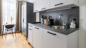 Uma cozinha moderna com pia de aço inoxidável, armários brancos e um espaço de refeições com mesa e cadeira.